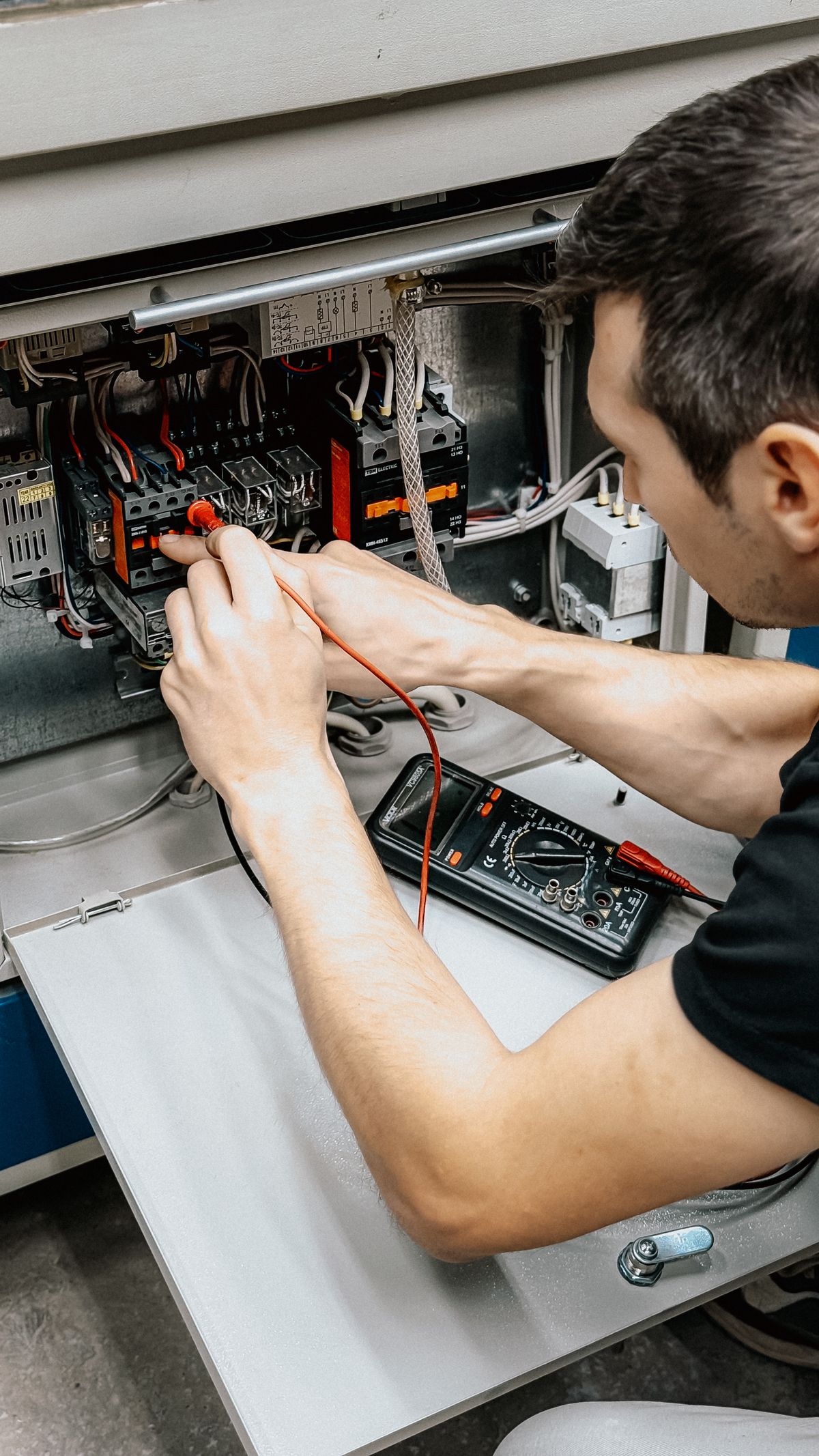 Techniker prüft eine elektrische Anlage mit einem Multimeter